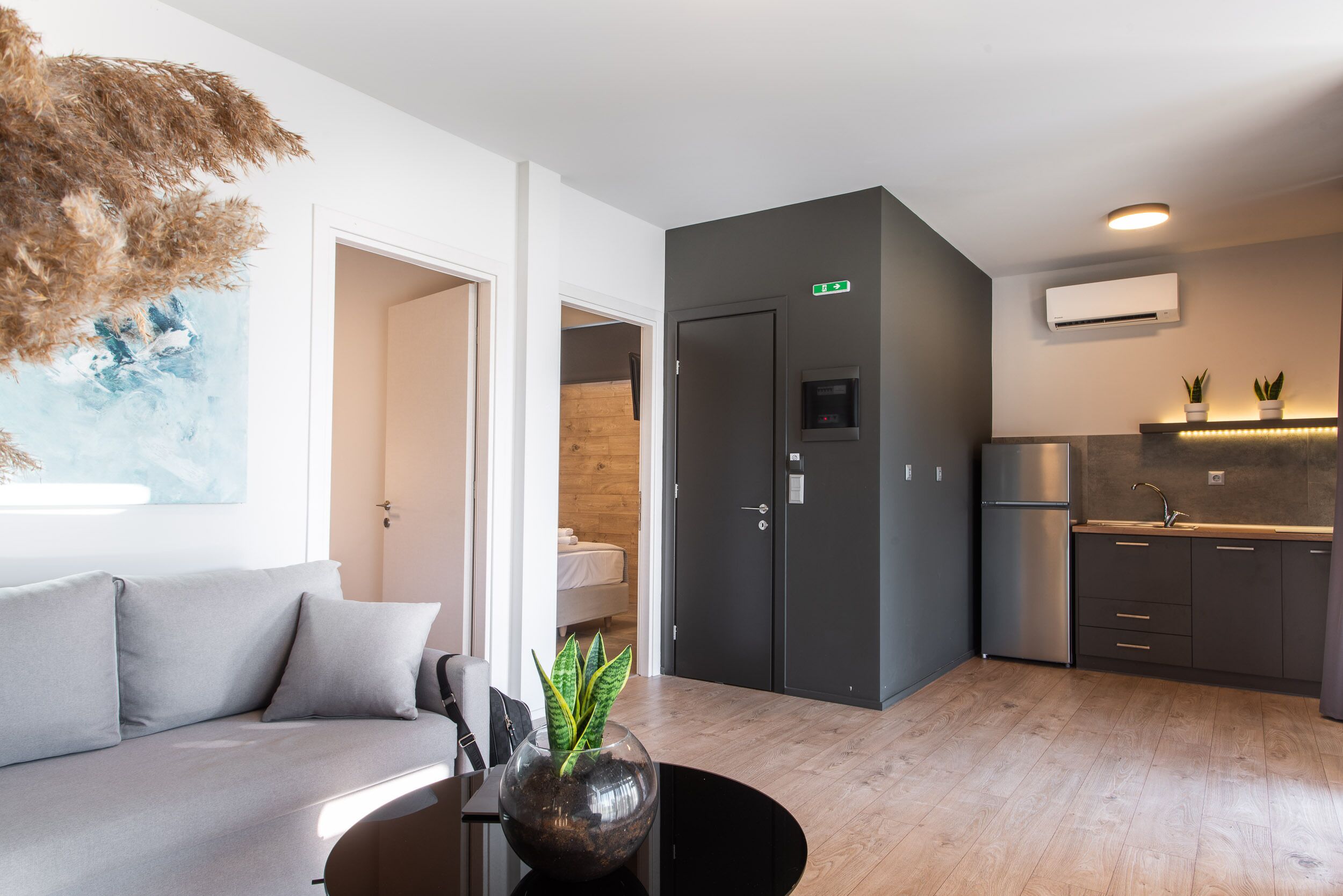 Una cucina moderna con mobili scuri, forno integrato e frigorifero in acciaio inossidabile.