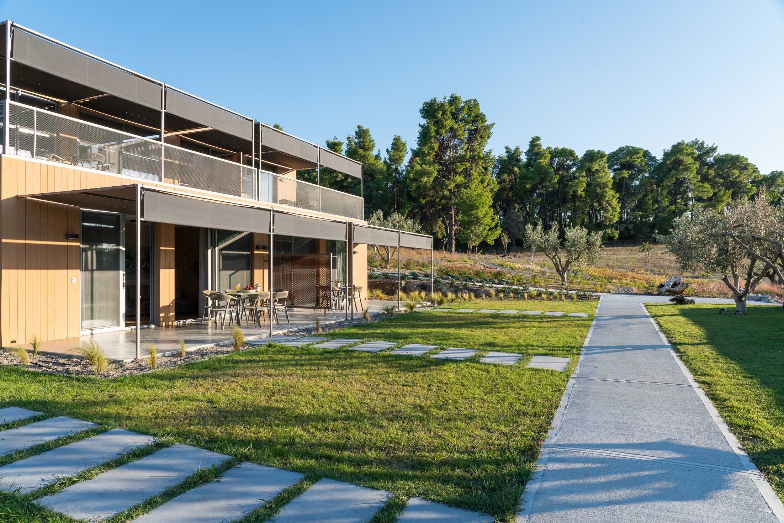 A modern two-story building with a covered outdoor seating area and a paved walkway.
