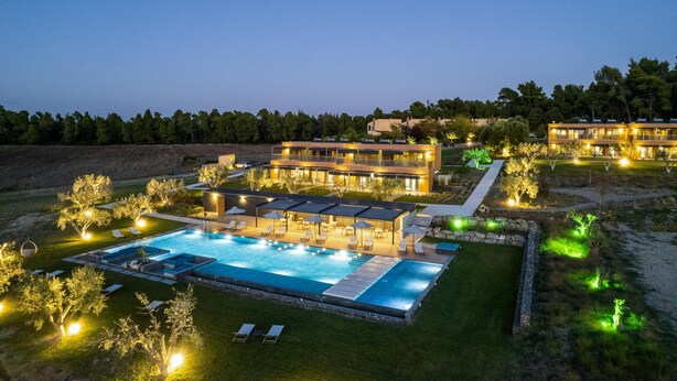Un hôtel moderne doté d’une piscine, d’un espace extérieur aménagé et de chemins bien éclairés.