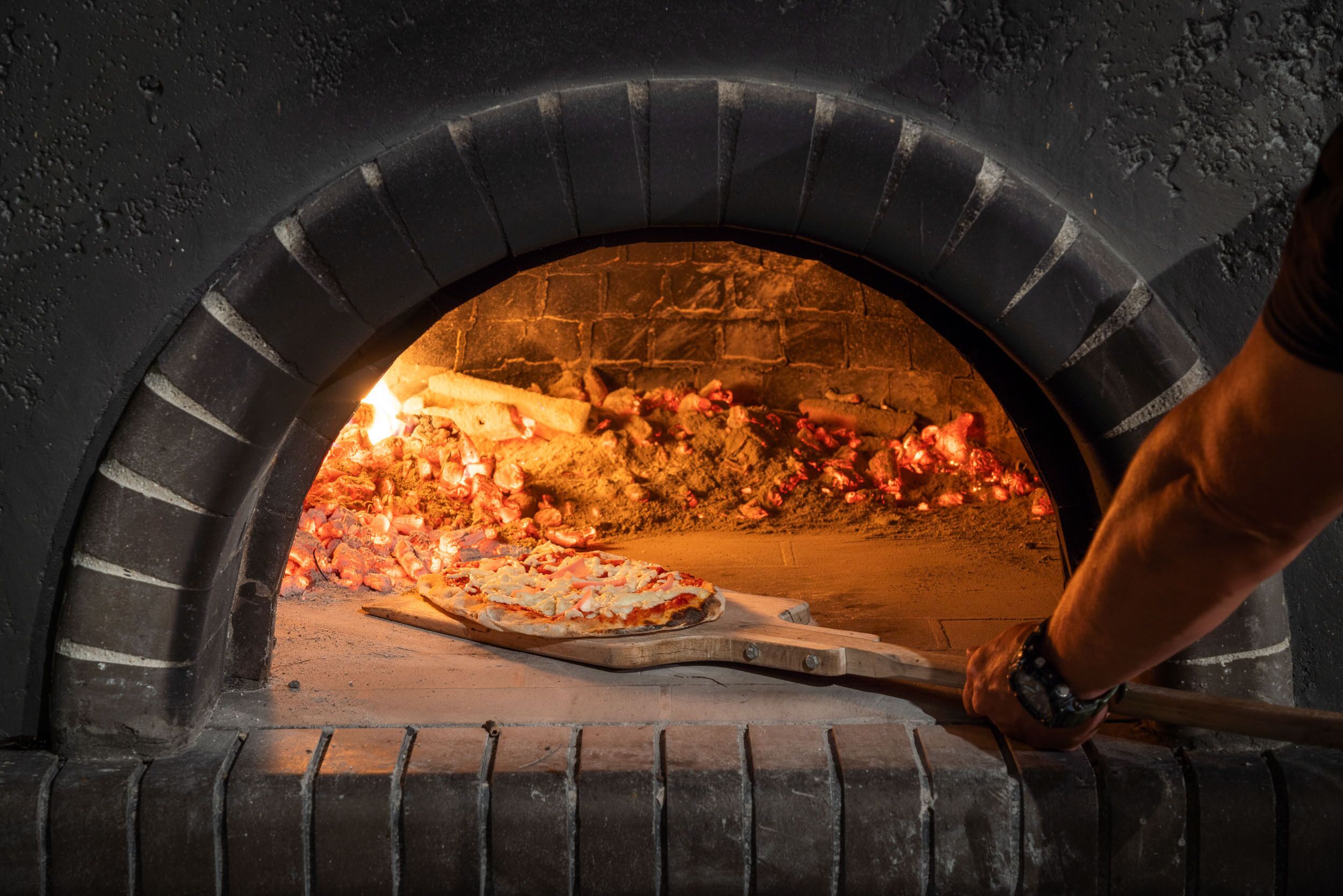 A pizza oven with a pizza being baked inside.