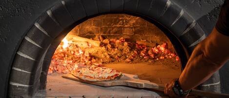 A pizza oven with a pizza being baked inside.