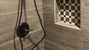 Um chuveiro com borrifador manual, design de azulejos xadrez e parede de madeira.