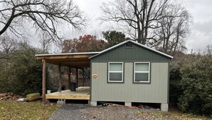 A small, single-story building with a covered porch and two windows. - Magnolia Cabin (Johnson City)