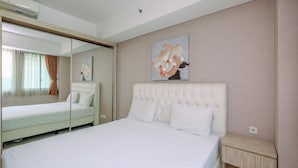 Een hotelkamer met een groot bed, een nachtkastje, een spiegel en een schilderij aan de muur.