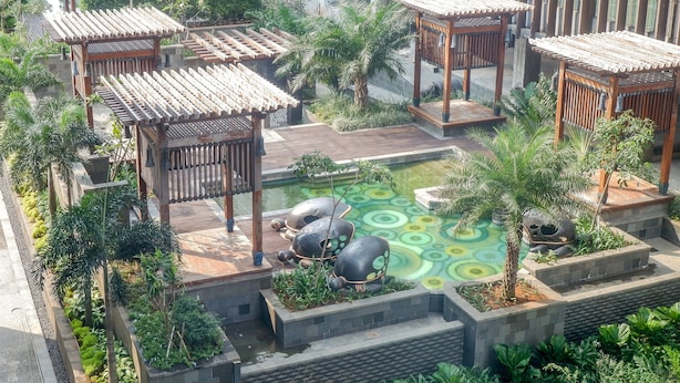 Een dakbostuin met houten pergola’s, een centraal waterpartij en omliggend groen.
