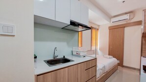A compact kitchen with a sink, cabinets, and a built-in stove. - Comfort and Cozy Studio Apartment at B Residence (Pagedangan)