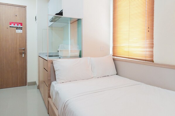 Un dormitorio con una cama, un armario de madera, un espejo y una ventana con persianas.