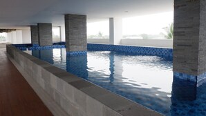 Una piscina interna con acqua cristallina, pareti piastrellate e pilastri in cemento.