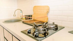 Una cucina con un lavandino, un portabacchette in legno e una stufa a gas.
