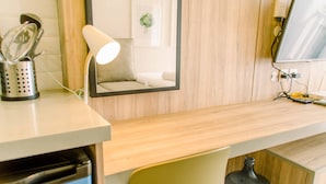 Angolo cottura con piano in legno, lavello, specchio e dispenser d'acqua.
