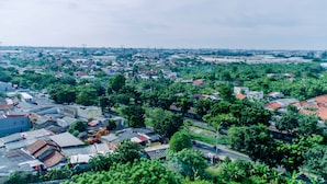 Una vista aerea di una zona urbana densamente popolata con edifici residenziali e commerciali, circondata dal verde.
