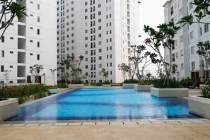 A swimming pool surrounded by planters and greenery, with high-rise buildings in the background. - Minimalist and Warm 2BR Bassura City Apartment (Jakarta)