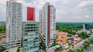 A high-rise building with multiple floors, large windows, and a prominent red section on the side. - Restful and Tidy Studio at Evenciio Margonda Apartment (Depok)