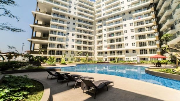 En flervåningsbostadsbyggnad med en swimmingpool och ett utomhusområde med sittplatser.