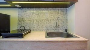 A kitchen with a tiled backsplash, a stainless steel sink, and a countertop. - Cozy Stay and Tidy Studio at Evenciio Margonda Apartment (Depok)