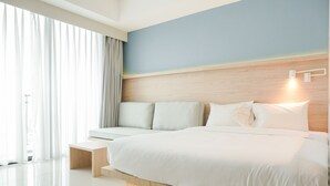 Un dormitorio moderno con una cama grande, cabecera de madera y vistas al exterior a través de amplios ventanales.