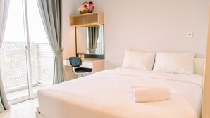 Ein Hotelzimmer mit einem großen Bett, einem Schreibtisch, einem Stuhl, einem Spiegel und Blick ins Freie.