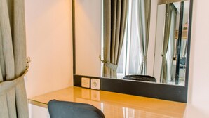 Ein Hotelzimmer mit einem Glastisch, einem schwarzen Sessel, einem großen Spiegel und einem Fenster mit Vorhängen.