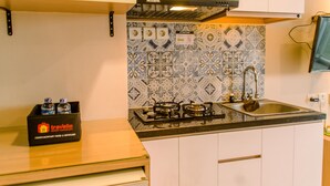 Eine Küche mit weißen Schränken, einer schwarzen Arbeitsplatte, einem Gasherd und einer gefliesten Spritzschutzwand.