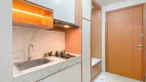 A modern kitchen with a built-in sink, wooden cabinets, and a countertop. - Comfortable and Minimalist Studio Apartment at Woodland Park Residence (Jakarta)