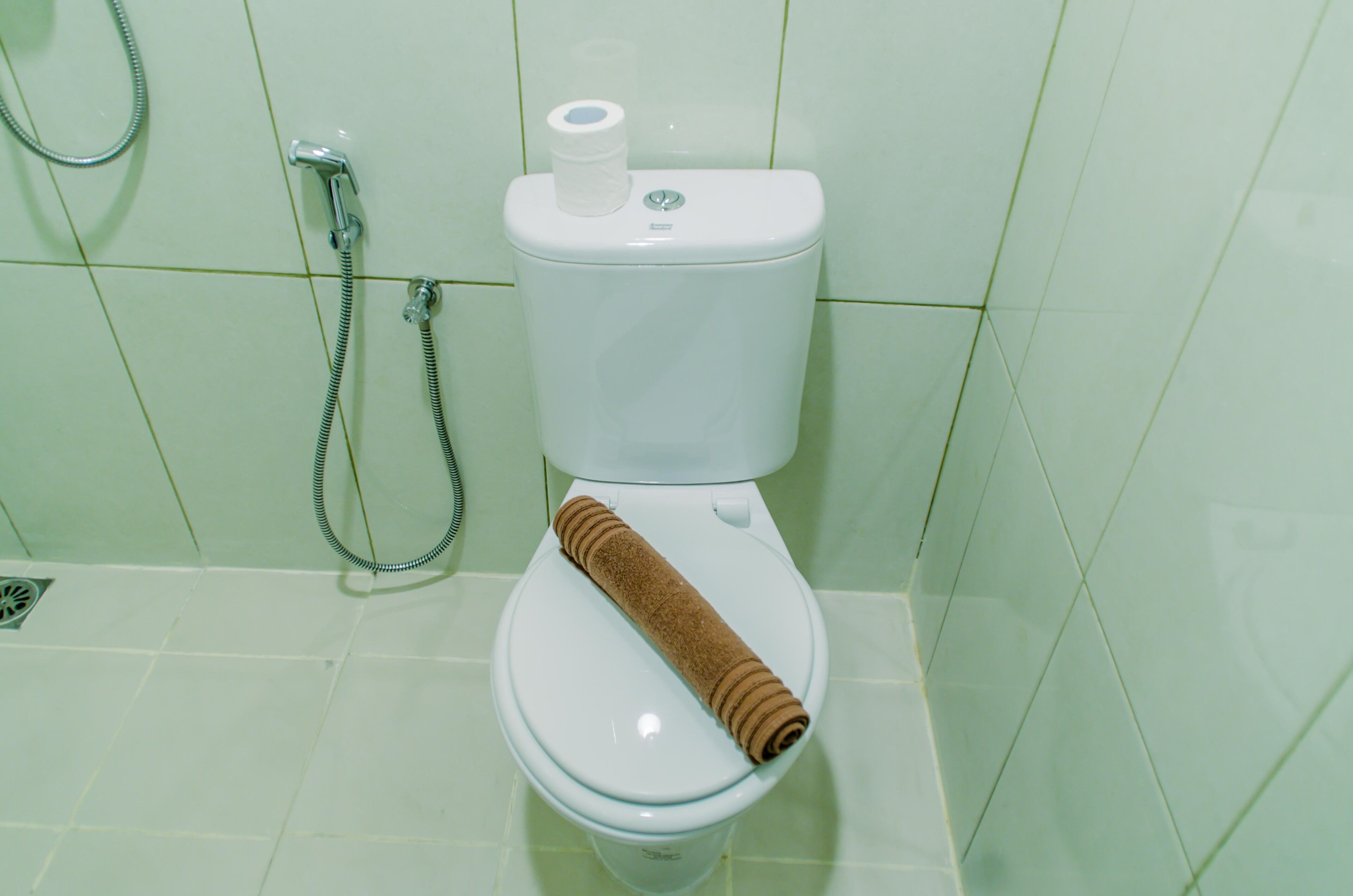 A toilet with a paper towel holder and a towel on the seat.