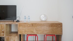 Un bureau en bois sur lequel sont posés une horloge et deux bouteilles d’eau.