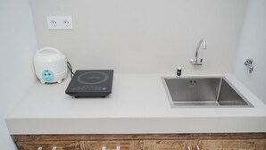 Une cuisine avec un plan de travail blanc, un évier en acier inoxydable, des placards en bois et un grille-pain.
