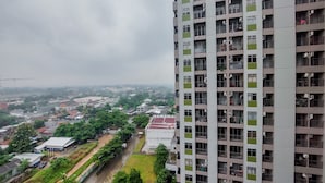 A high-rise building with multiple balconies, surrounded by greenery and other buildings. - Nice and Spacious 2BR at Serpong Greenview Apartment (South Tangerang)