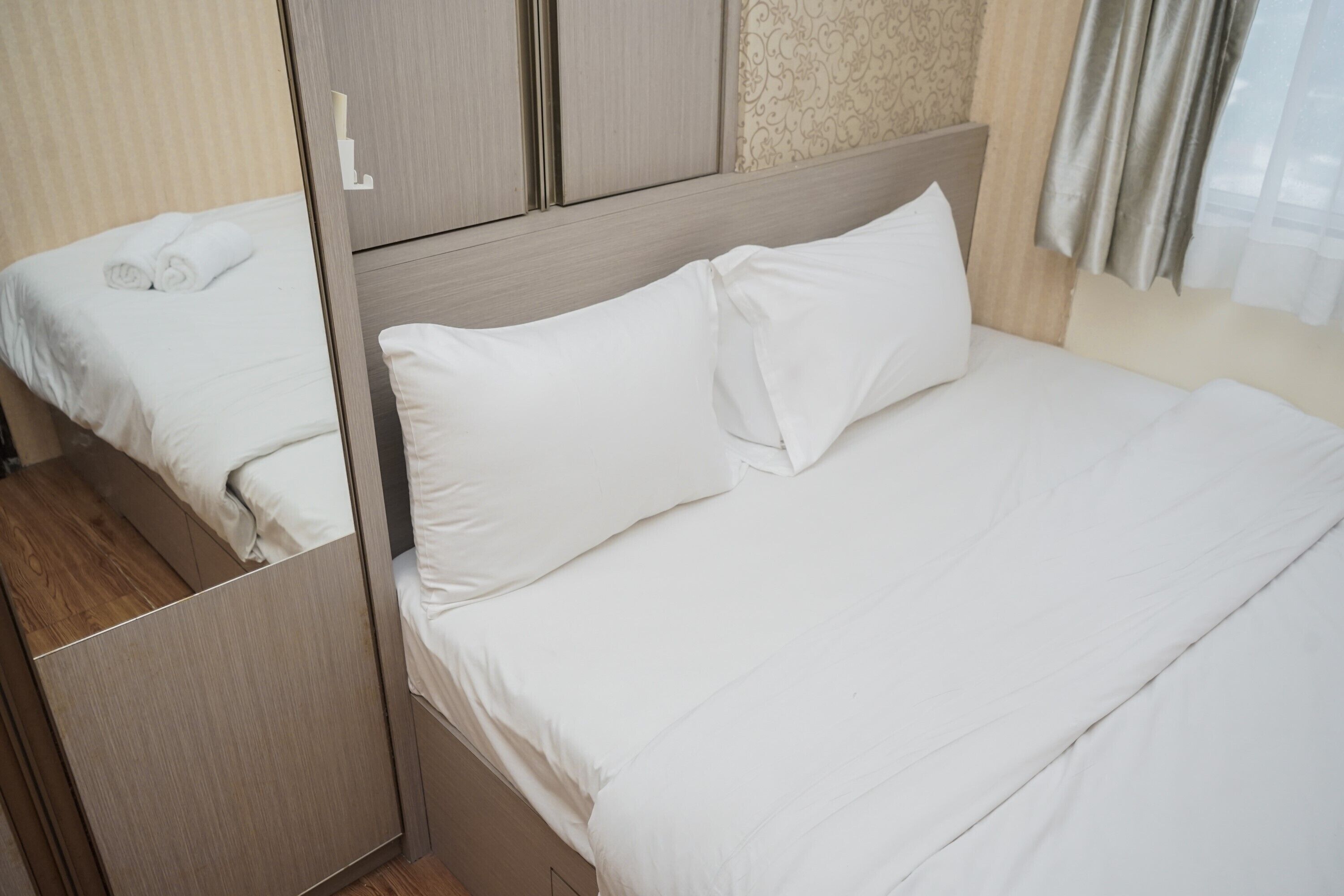 Cama bem arrumada com lençóis brancos em um quarto de hotel.