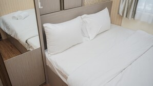 A neatly made bed with white linens in a hotel room. - Nice and Spacious 2BR at Serpong Greenview Apartment (South Tangerang)
