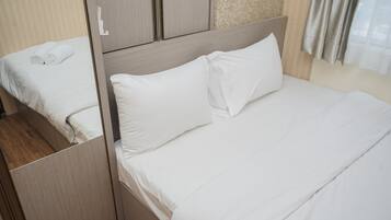Cama bem arrumada com lençóis brancos em um quarto de hotel.