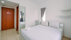 A hotel room with a bed, a nightstand, a mirror, a door, and a window with curtains. - Simple and Cozy Living Studio Apartment at Margonda Residence (Depok)