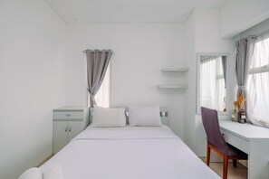 A bedroom with a bed, a desk, and a chair.