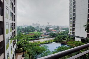 Un edificio alto con vistas a una zona ajardinada que incluye un estanque y follaje.