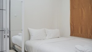 Ein Schlafzimmer mit einem Bett, weißer Bettwäsche, einem Kleiderschrank und einem Vorhang.