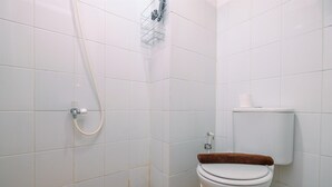 A small, clean bathroom with white tiles, a toilet, a shower, and a towel rack. - Modern and Homey Studio at Gunung Putri Apartment (Gunung Putri)