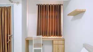 A bedroom with a wooden desk, a chair, a bed, and a window with curtains. - Modern and Homey Studio at Gunung Putri Apartment (Gunung Putri)