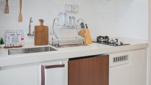 A modern kitchen with a stainless steel sink, wooden cutting board, knife holder, and a sign with kitchen rules.