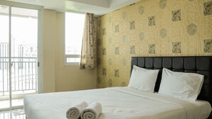 Ein Hotelzimmer mit einem großen Bett, einer Wand mit Muster und Blick durch ein Fenster.