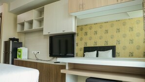 Ein Hotelzimmer mit Bett, Fernseher, Schreibtisch und Kleiderschrank.