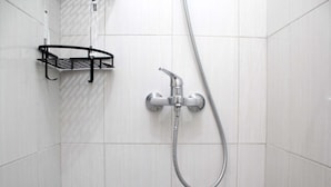 A shower area with a metal rack and a handheld showerhead.
