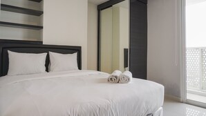 A modern hotel room with a large bed, a black headboard, and a large mirror. - Fancy and Nice Studio at West Vista Apartment (Jakarta)