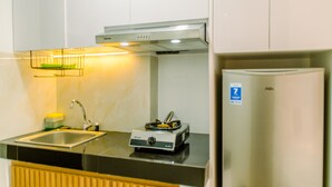 A kitchen with a sink, stove, and refrigerator. - Homey and Cozy Stay Studio Room at Serpong Garden Apartmen (Cisauk)