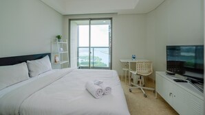 Ein Hotelzimmer mit Bett, Fernseher, Schreibtisch und Blick ins Freie.