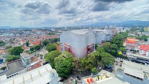 Une vue urbaine mettant en scène un bâtiment moderne imposant, entouré d’arbres et de bâtiments plus petits.