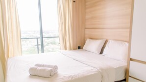 Habitación de hotel con una cama grande, ropa de cama blanca y vistas a la ciudad a través de la ventana.