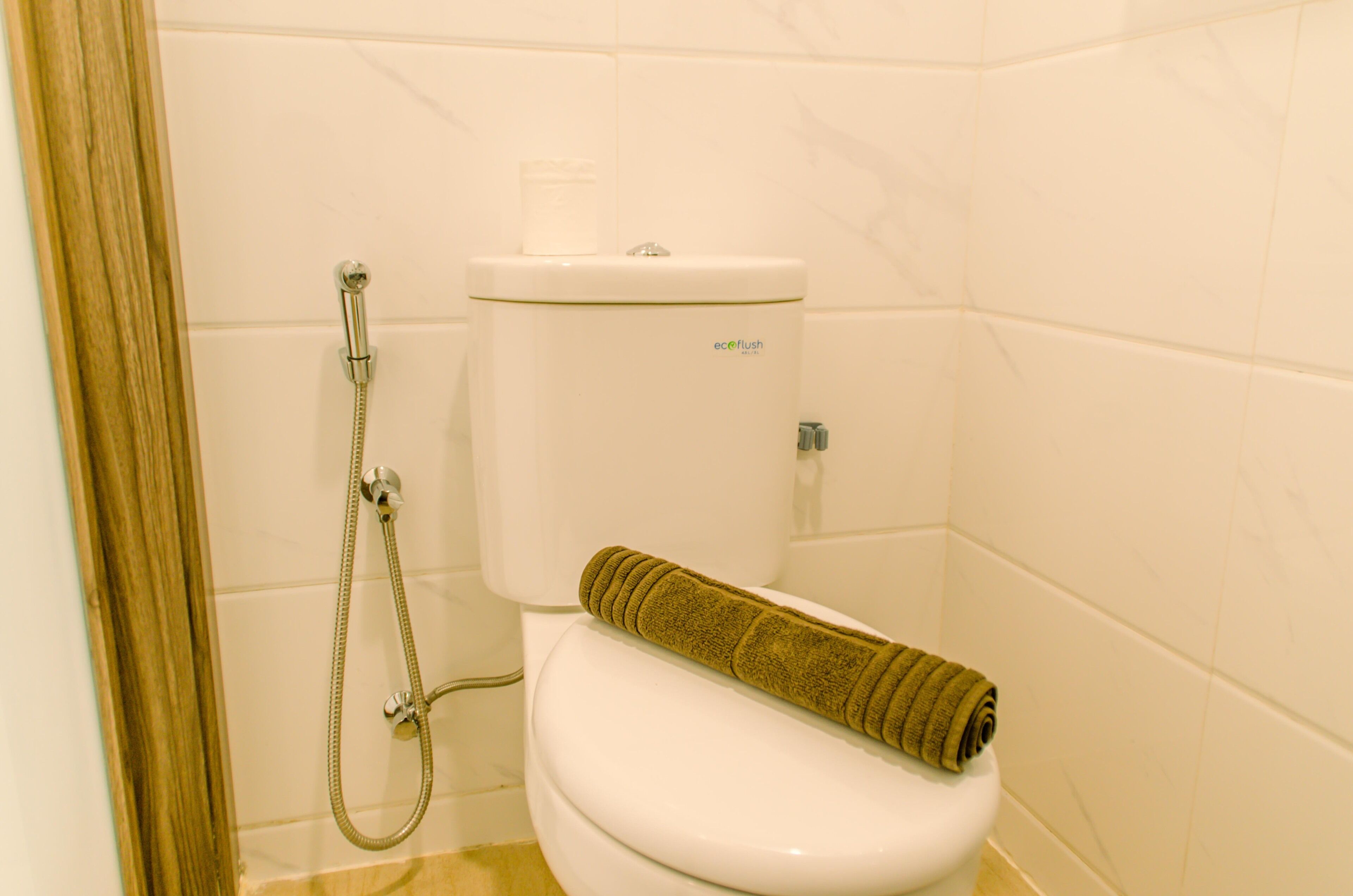 A bathroom with a toilet, a shower, and a towel on the seat.