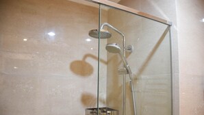 A glass-enclosed shower with a handheld showerhead and a wall-mounted faucet. - Fully Furnished with Cozy Design Studio at Menteng Park Apartment (Jakarta)