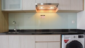 A kitchen with a stainless steel sink, a built-in oven, and a front-loading washing machine. - Fully Furnished with Cozy Design Studio at Menteng Park Apartment (Jakarta)
