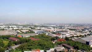 Een stadsgezicht met een combinatie van woon- en bedrijfsgebouwen, waaronder een groot industriegebied en enkele groene elementen.